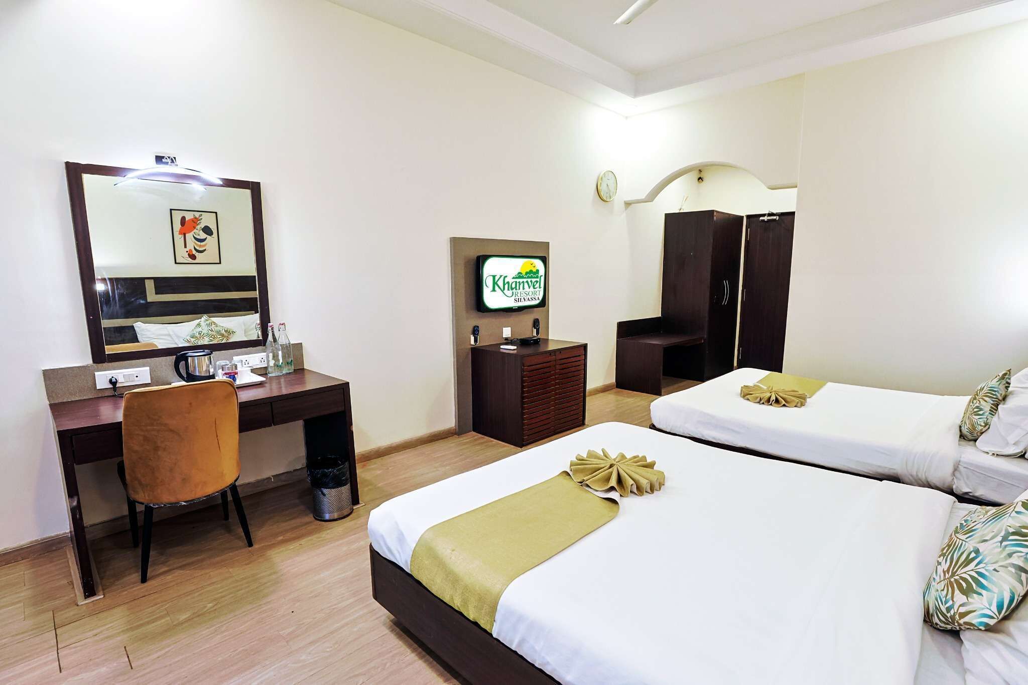 Une chambre d’hôtel équipée d’un bureau, de deux lits, d’une télévision et d’une armoire.