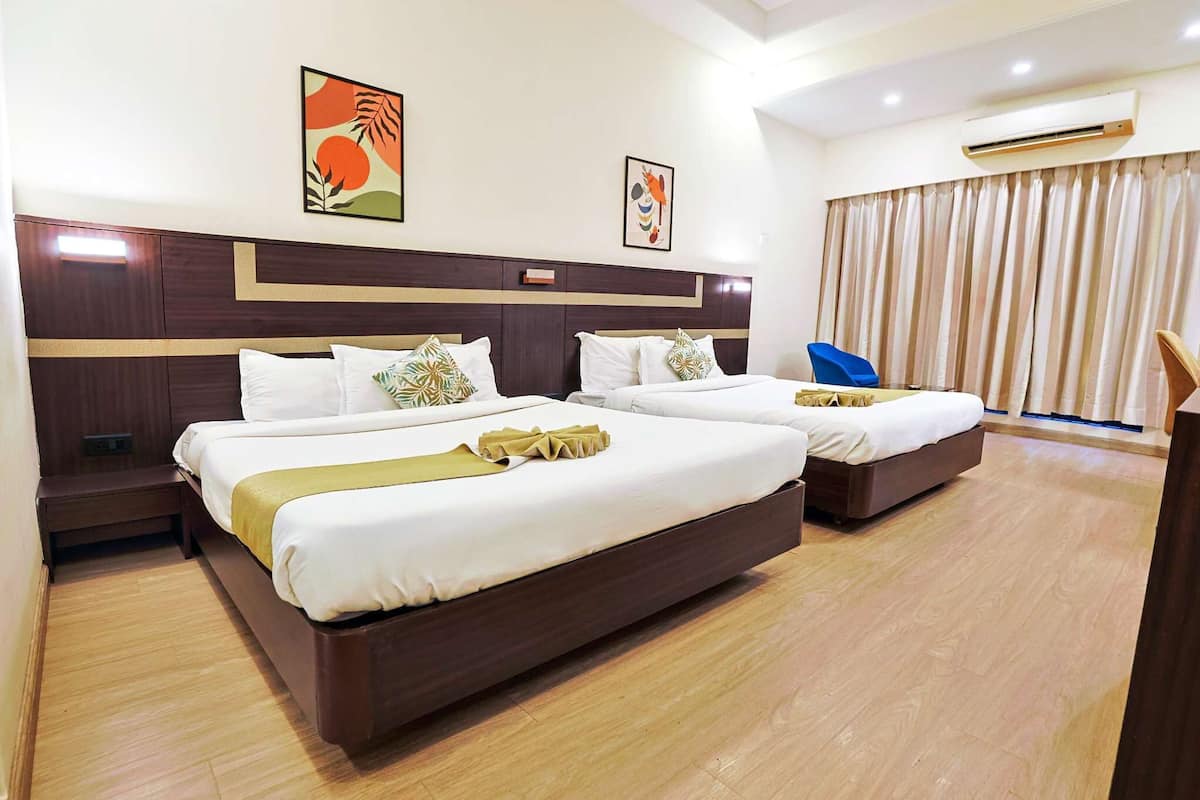 A hotel room with two beds, a wooden headboard, a blue chair, and a large window with curtains.