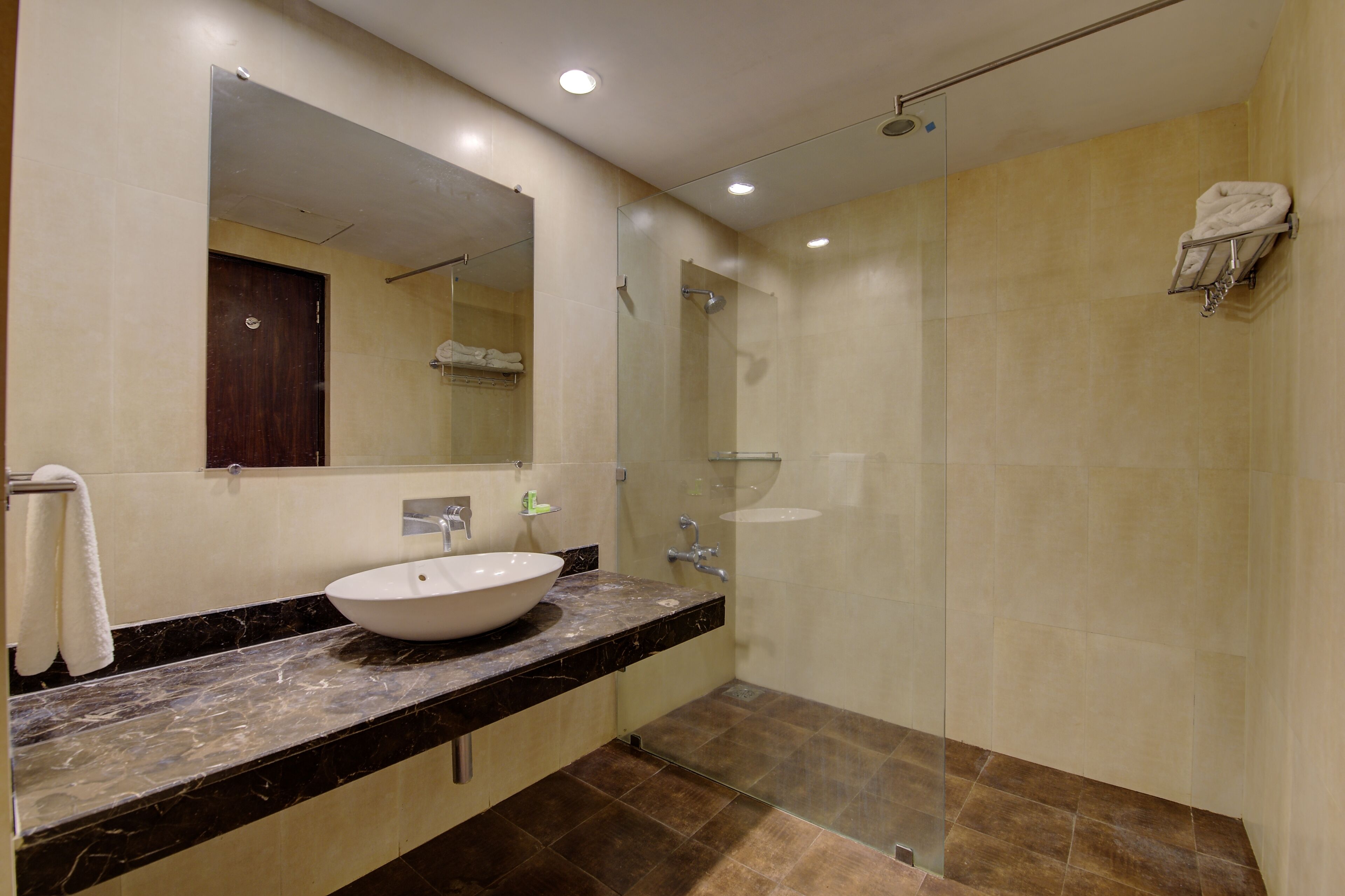 Un baño moderno con un espejo grande, un lavabo y una ducha con cerramiento de vidrio.