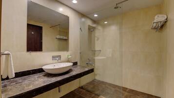 Un baño moderno con un espejo grande, un lavabo y una ducha con cerramiento de vidrio.