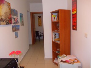 Un pasillo con una estantería de madera, una silla y un escritorio con computadora y flores.