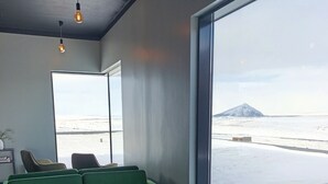 Et værelse med en grøn sofa, to lænestole, et lille bord og et stort vindue med udsigt over et sneklædt landskab.
