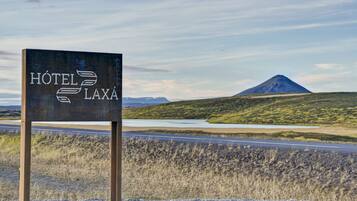 Schild für ein Hotel namens "Hôtel Laxá" mit Blick auf einen Berg und eine Straße im Hintergrund.