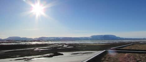 Un paisaje con cielo despejado, montañas lejanas y una masa de agua que refleja la luz del sol.