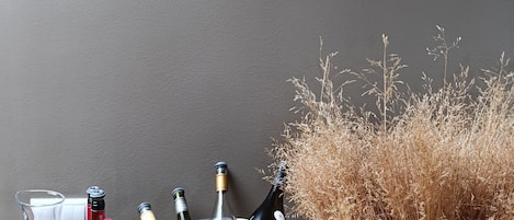 A table with a metal bowl containing wine bottles, a wine opener, and a glass.