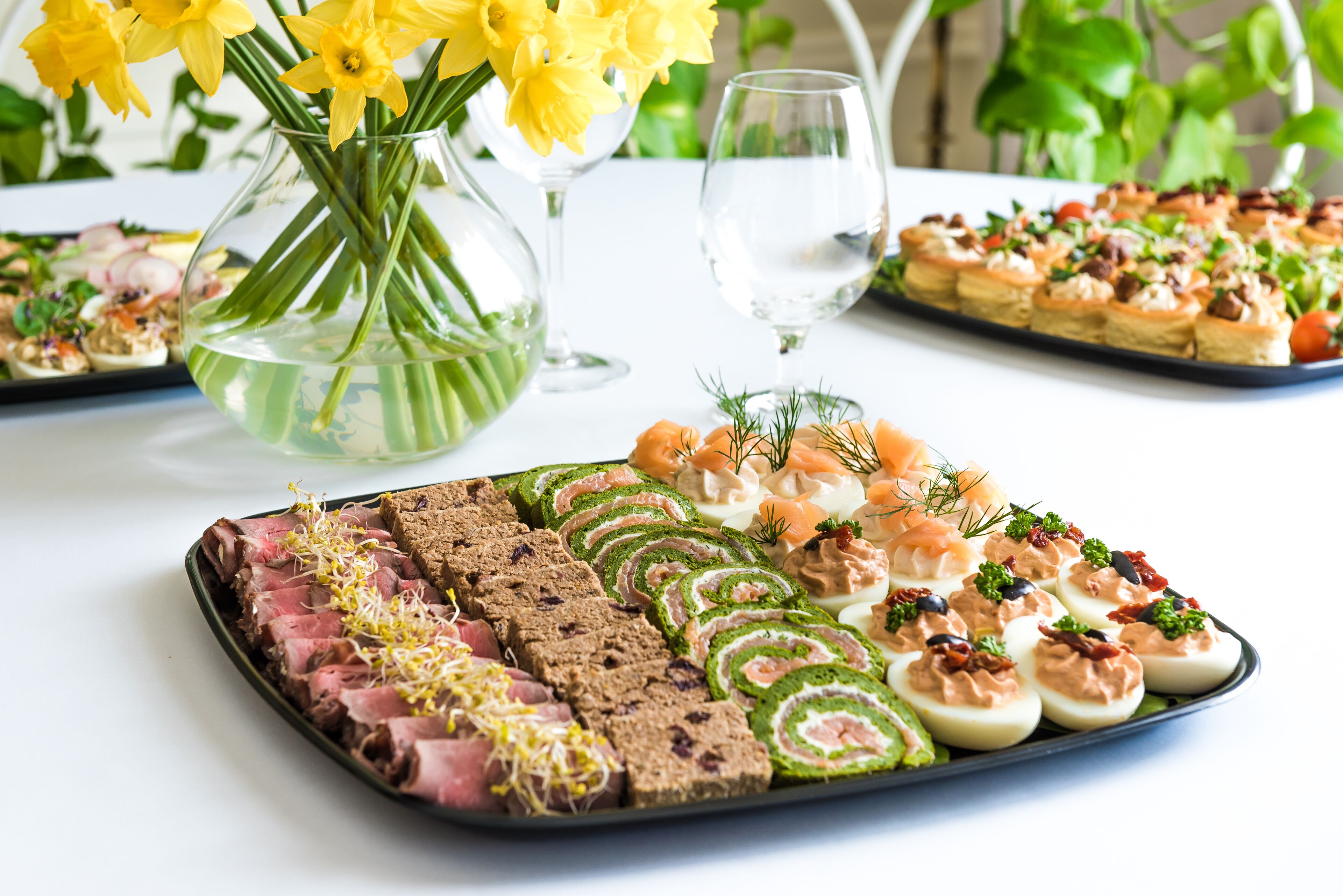 Une table avec divers aliments, un vase rempli de fleurs jaunes et un verre d’eau.