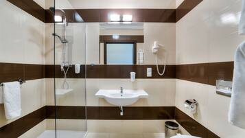 A modern bathroom with a glass-enclosed shower, a sink, and a toilet.
