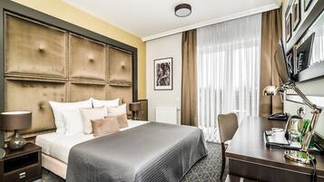 Habitación de hotel con una cama grande, un escritorio con lámpara, una silla y vistas al exterior a través de la ventana.