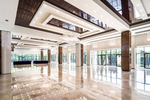 A spacious lobby with a high ceiling, large windows, and a polished floor.