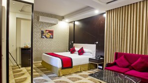 A hotel room with a bed, a nightstand, a red sofa, a coffee table, and a mirror. - Innotel Luxury Business Hotel (Dhaka)
