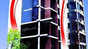 A modern multi-story building with a distinctive red and white design on the facade, featuring a mix of glass and brick elements. - Innotel Luxury Business Hotel (Dhaka)