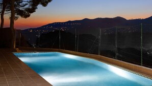A swimming pool with a clear view of distant city lights and mountains. - Hotel Porta d'Alella (Alella)