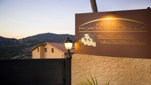 A sign for Hotel Portad'allea Restaurant Les Terrasses with a view of a mountain in the background. - Hotel Porta d'Alella (Alella)