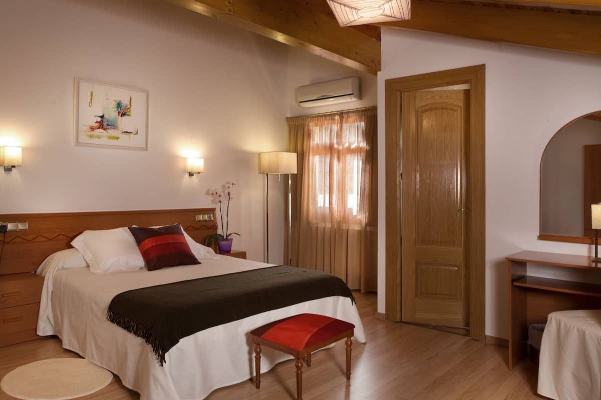A hotel room with a bed, bedside lamps, a desk, and a mirror.