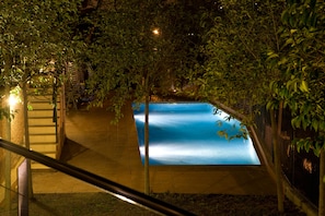 A swimming pool surrounded by trees at night. - Hotel Porta d'Alella (Alella)