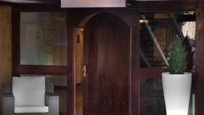 A reception area with a wooden door, a white potted plant, and a grey sofa. - Hotel Porta d'Alella (Alella)
