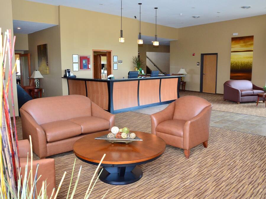 A hotel lobby with a reception desk, two leather sofas, a coffee table, and a large painting on the wall.