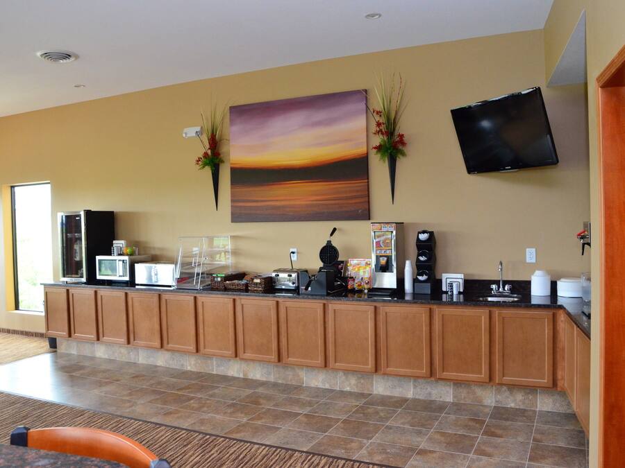 Een hotel lobby met een receptiebalie, een flatscreen televisie en een groot schilderij van een zonsondergang.