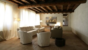 A spacious living room with a wooden ceiling, a sofa set, a coffee table, and a painting on the wall. - Relais Corte Guastalla (Sona)