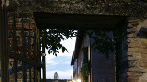 An open gate leading to a gravel path and a building with a brick facade. - Relais Corte Guastalla (Sona)