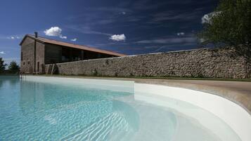 Una piscina con una parete in pietra e un edificio a tetto spiovente.