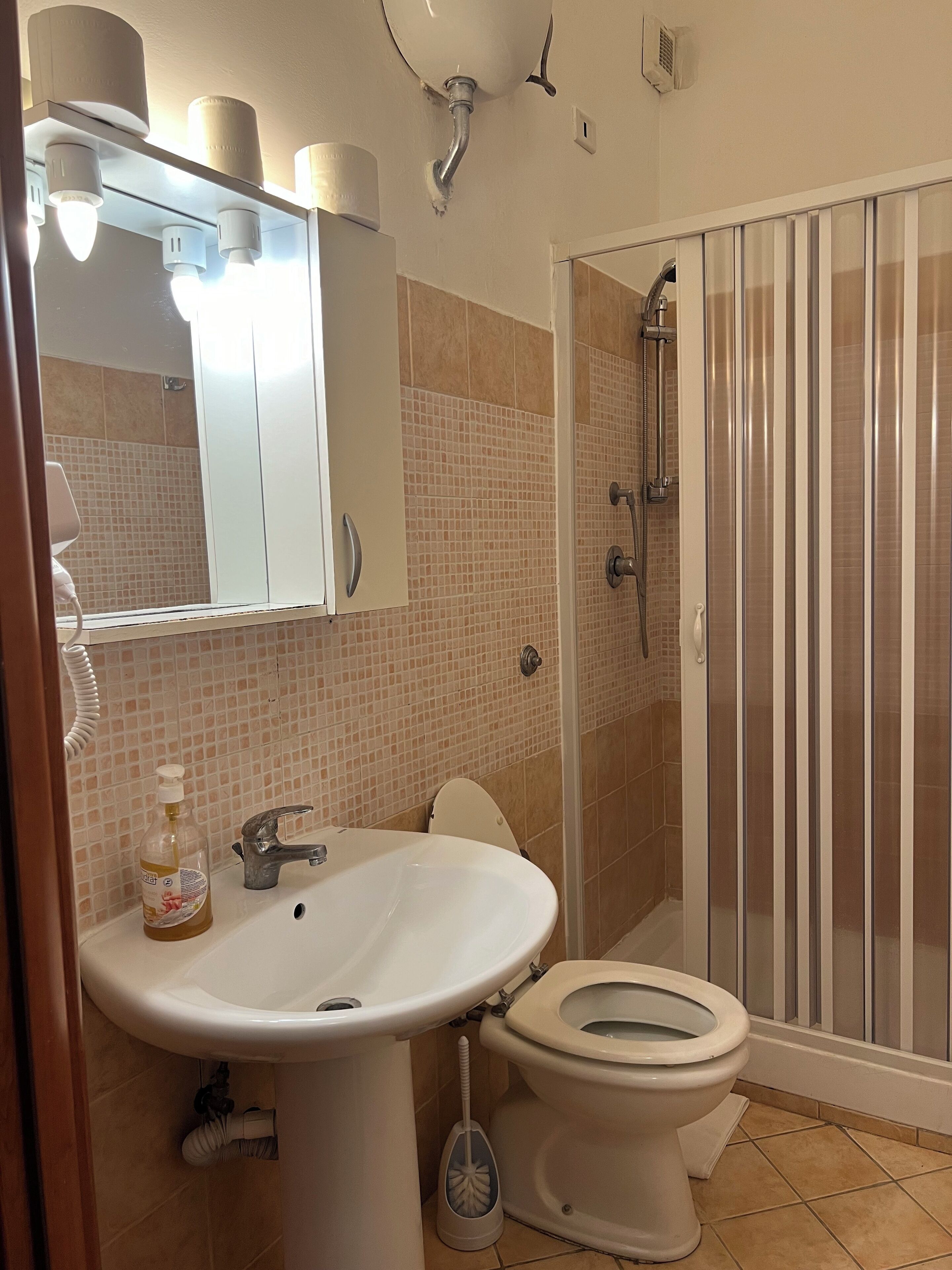 Un bagno con lavandino, WC e doccia.