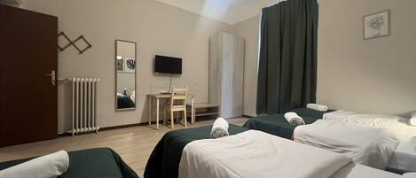 Une chambre d’hôtel avec deux lits, un bureau, une chaise, une télévision et une fenêtre avec des rideaux.