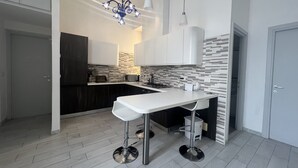 A modern kitchen with a white countertop, stainless steel appliances, and a patterned backsplash. - Freedom Traveller Hostel (Rome)