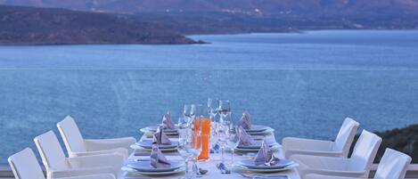 A table set for a meal with a view of a large body of water and mountains in the background.