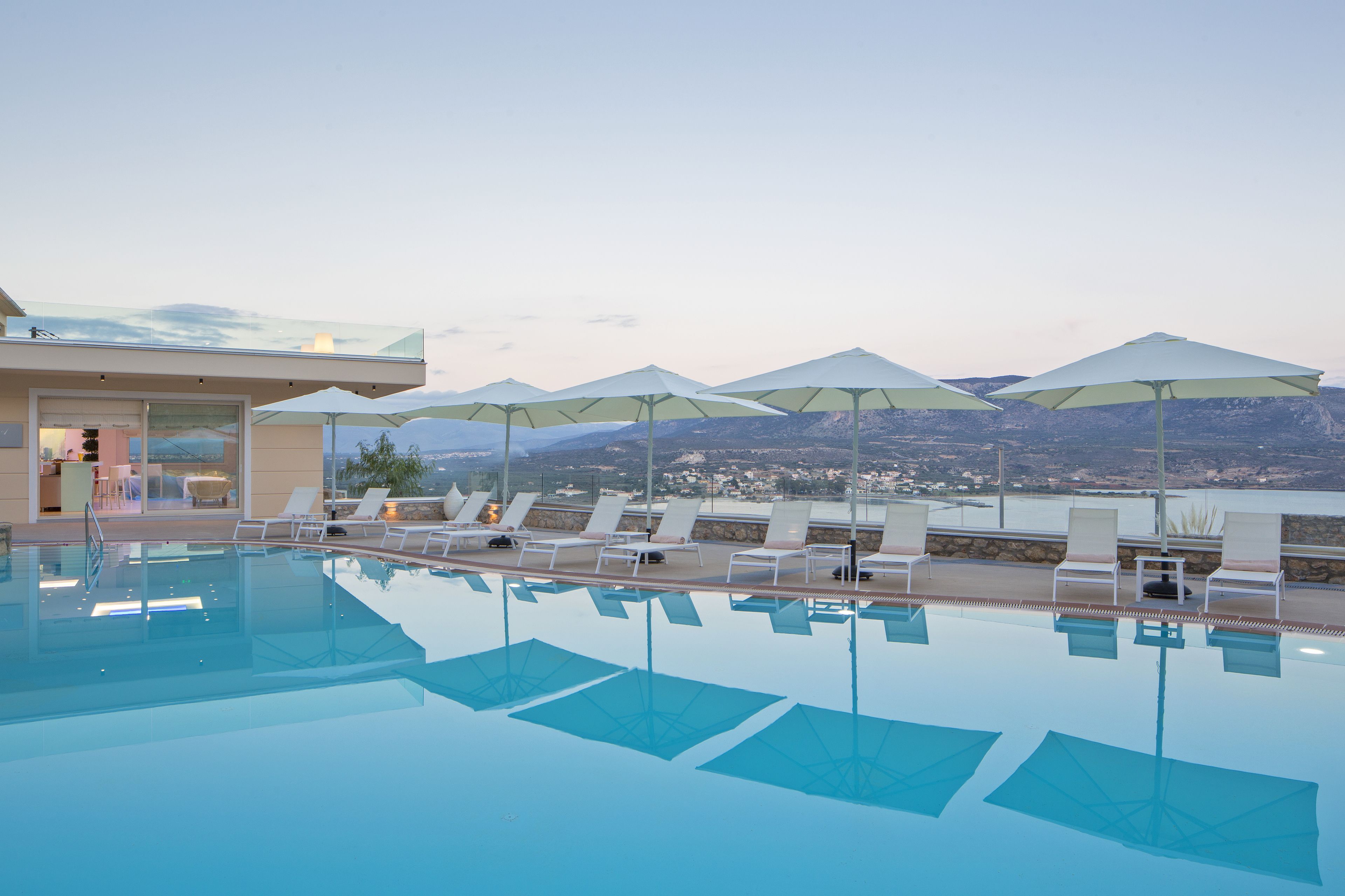 A pool area with lounge chairs and umbrellas, overlooking a mountainous landscape.