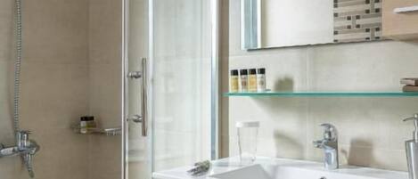 A bathroom with a glass shower enclosure, a sink with a mirror above, and a cabinet below.