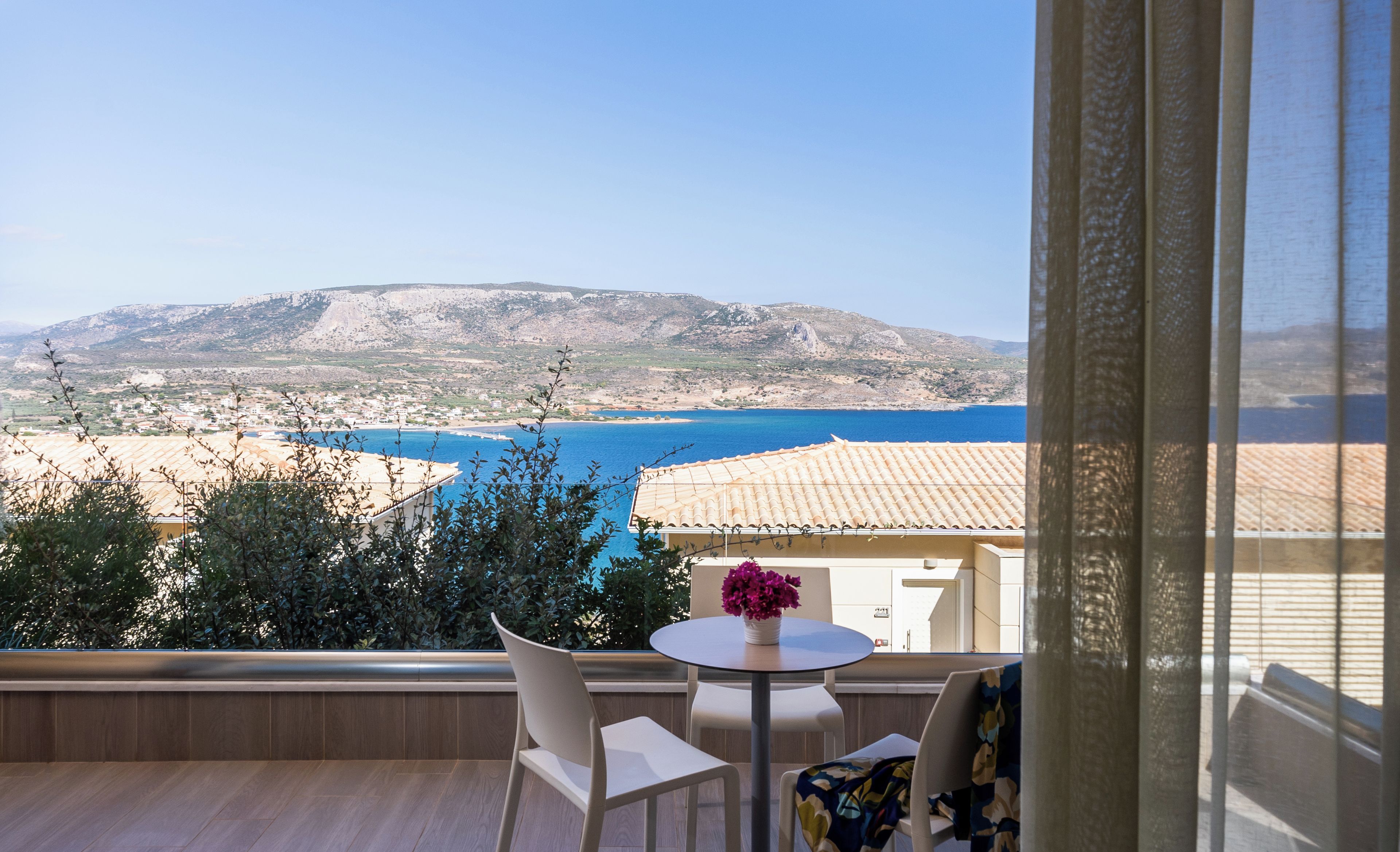 Un balcone con vista sul paesaggio costiero, che comprende una distesa d'acqua e colline in lontananza.