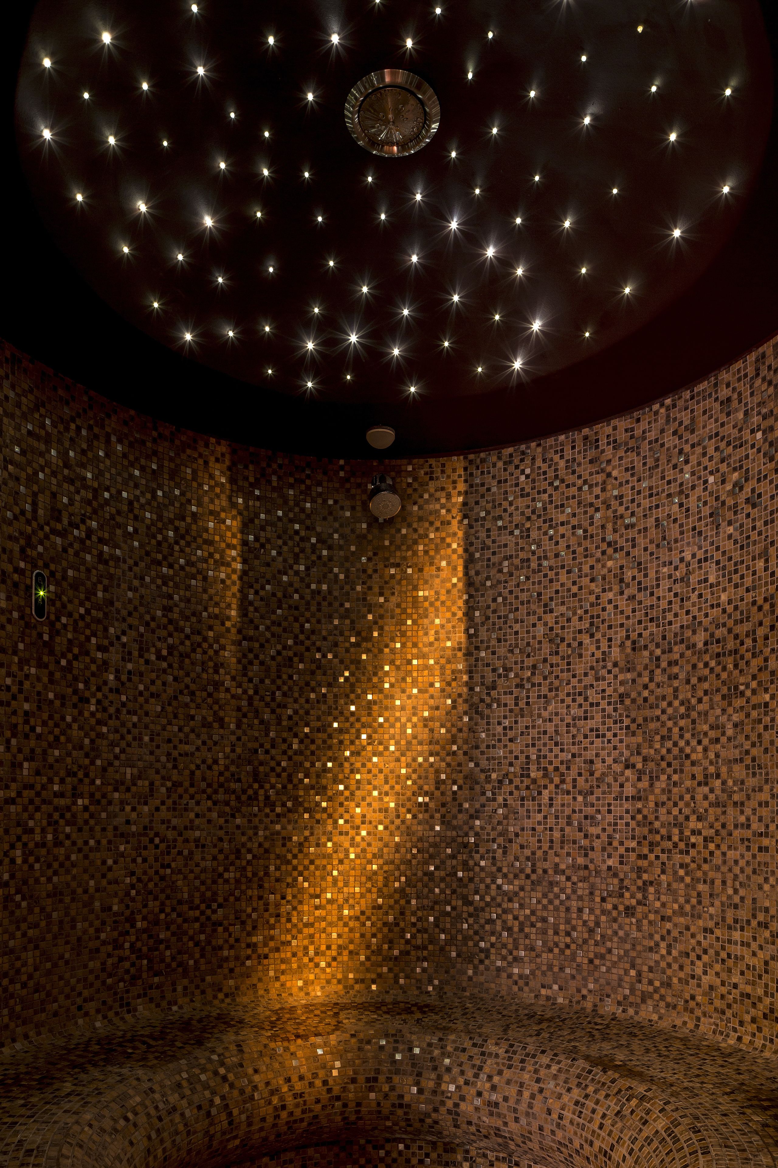 A room with a starry ceiling, a clock, and a mosaic wall.