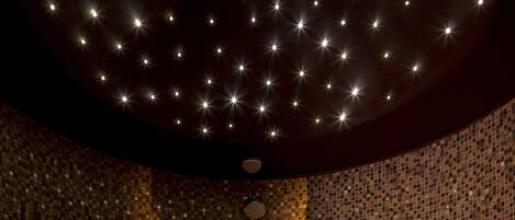Una habitación con techo estrellado, un reloj y una pared de mosaicos.