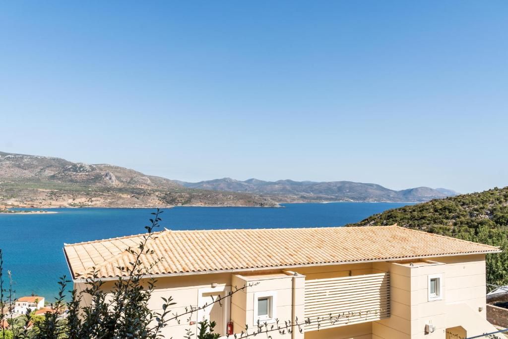 A coastal building with a tiled roof overlooking a body of water and hills.