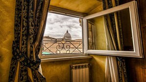 A window with a view of a domed building, curtains, and a radiator. - B&B A Picture of Rome (Rome)