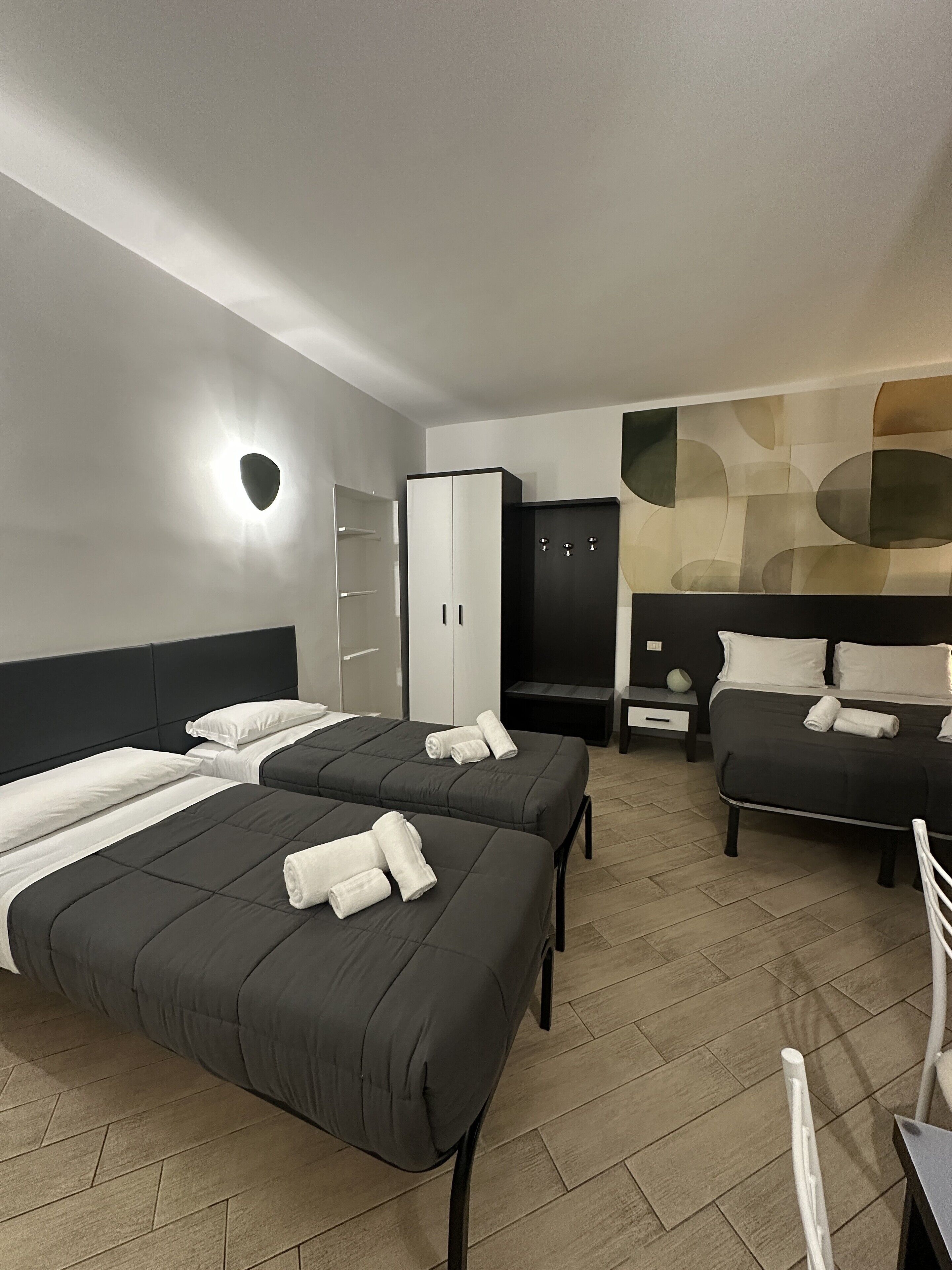 Habitación de hotel con dos camas, un armario, un escritorio y zona de estar.