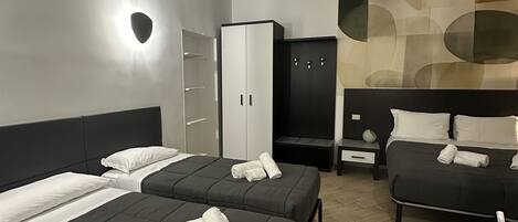 Habitación de hotel con dos camas, un armario, un escritorio y zona de estar.
