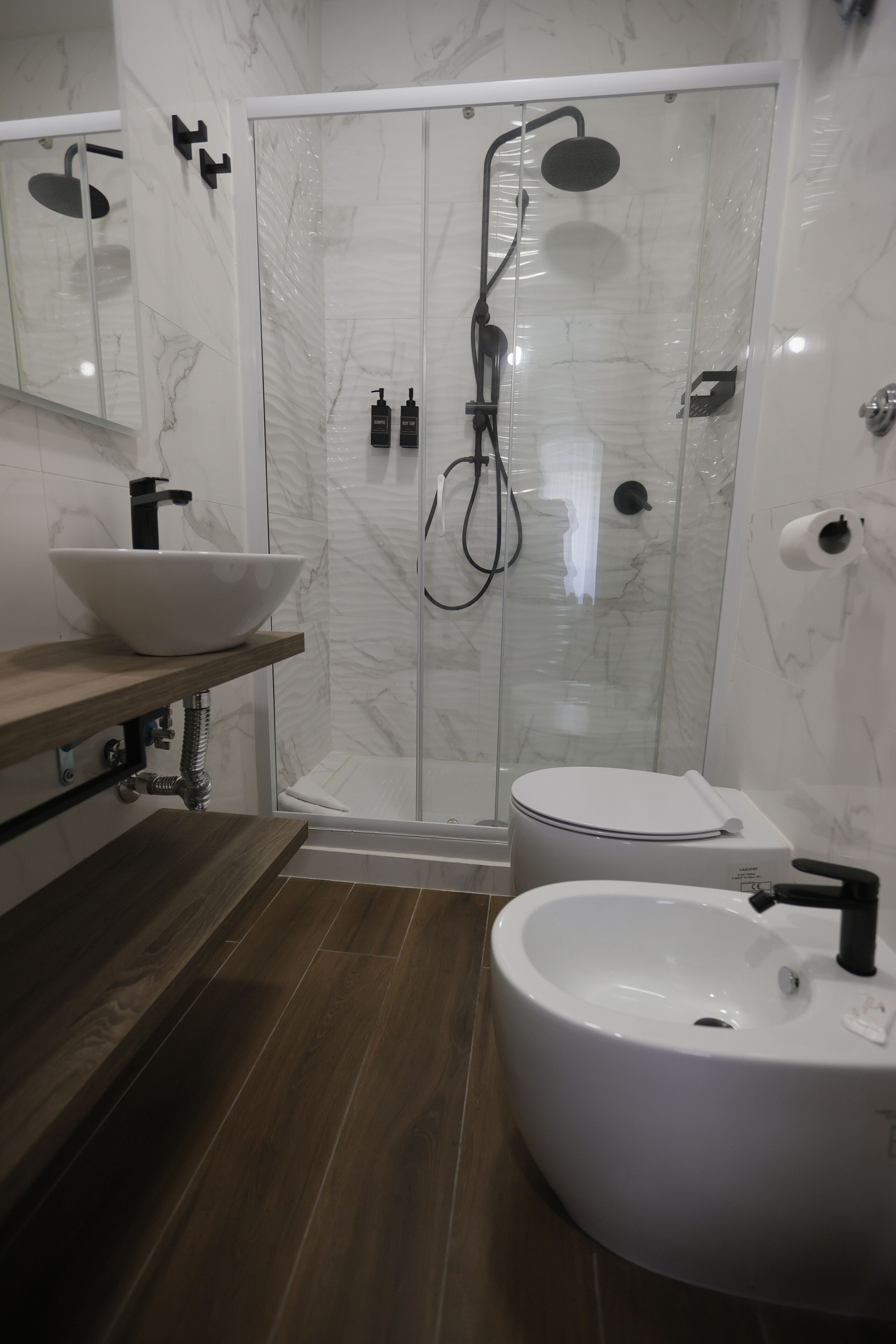 Un bagno moderno con doccia vetrata, un lavandino bianco e il water.