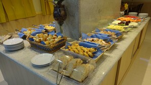 A buffet with various food items, including bread, pastries, and fruits. - Elegance Praia Hotel (Rio de Janeiro)