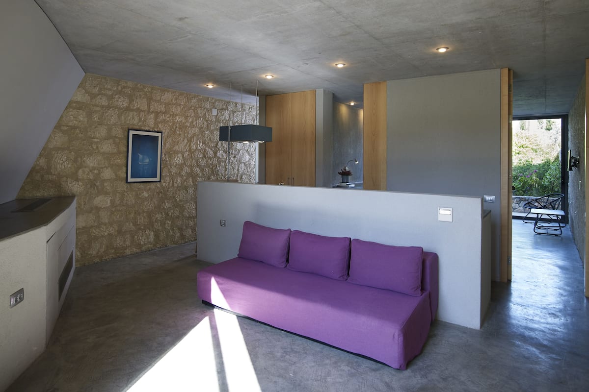 Un interior moderno con un sofá morado, una pared de piedra y una separación de madera.