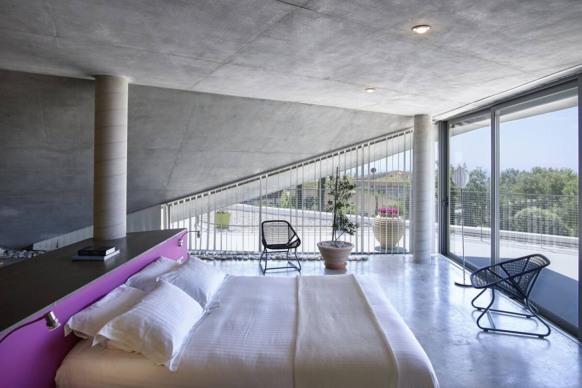 Una habitación de hotel moderna con una cama grande, un escritorio y un balcón con vistas.