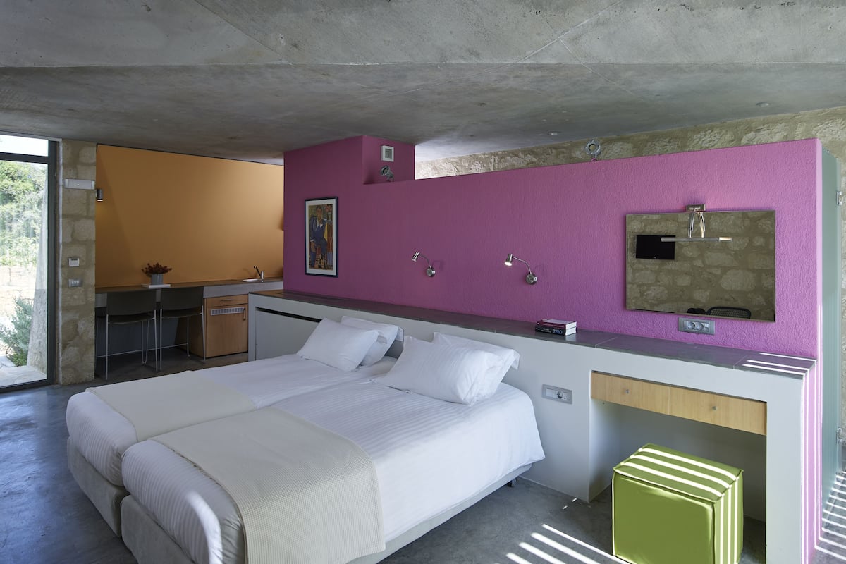 Un dormitorio moderno con una cama grande, un escritorio y un baño con lavamanos de piedra.