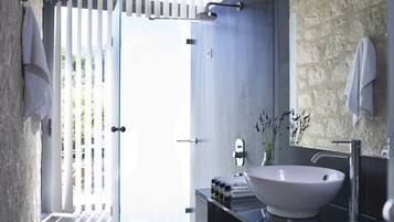 Un bagno moderno con un lavandino bianco di grandi dimensioni, un box doccia in vetro e una parete con texture in pietra.