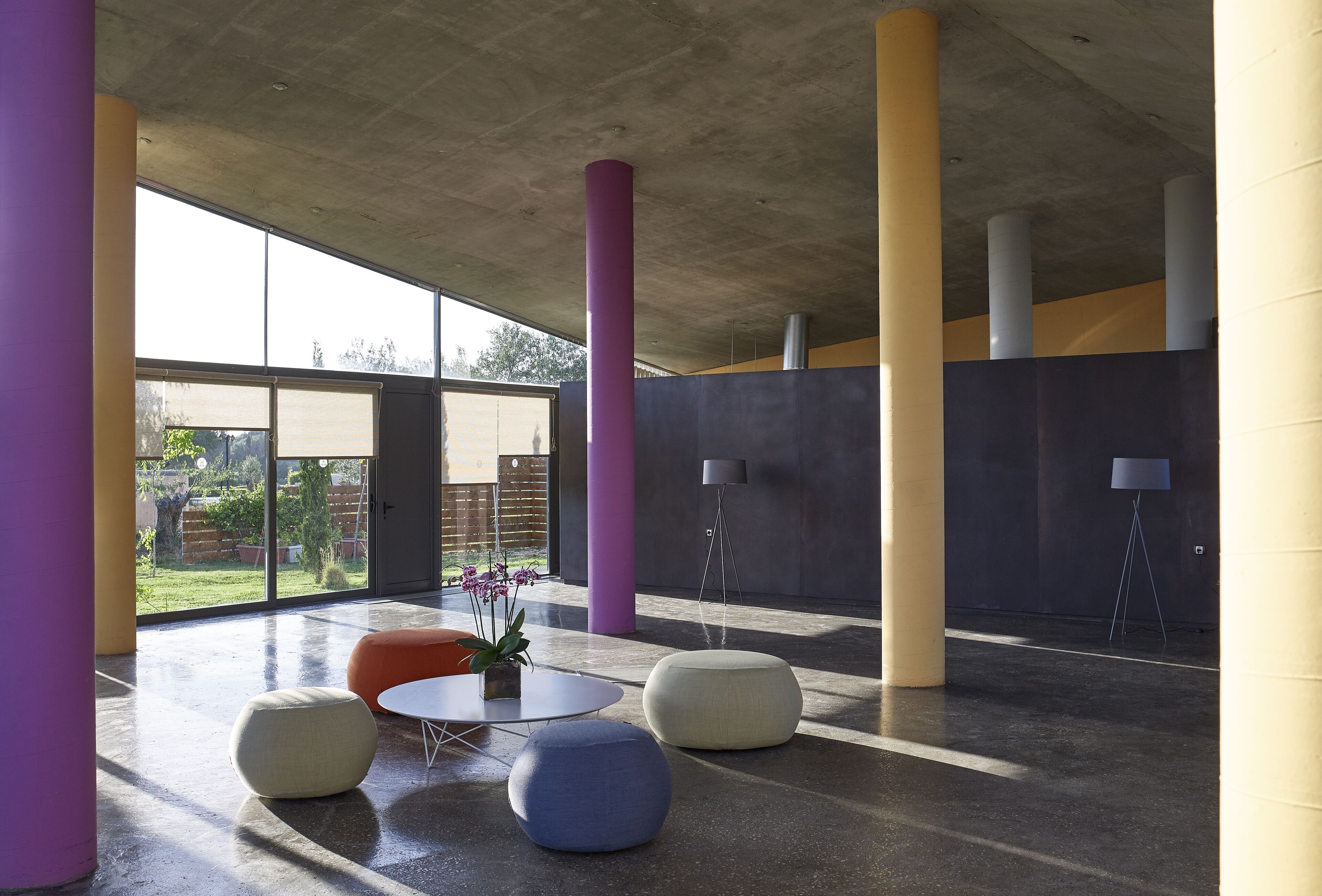 A spacious indoor area with large windows, a round table, and several seating options.
