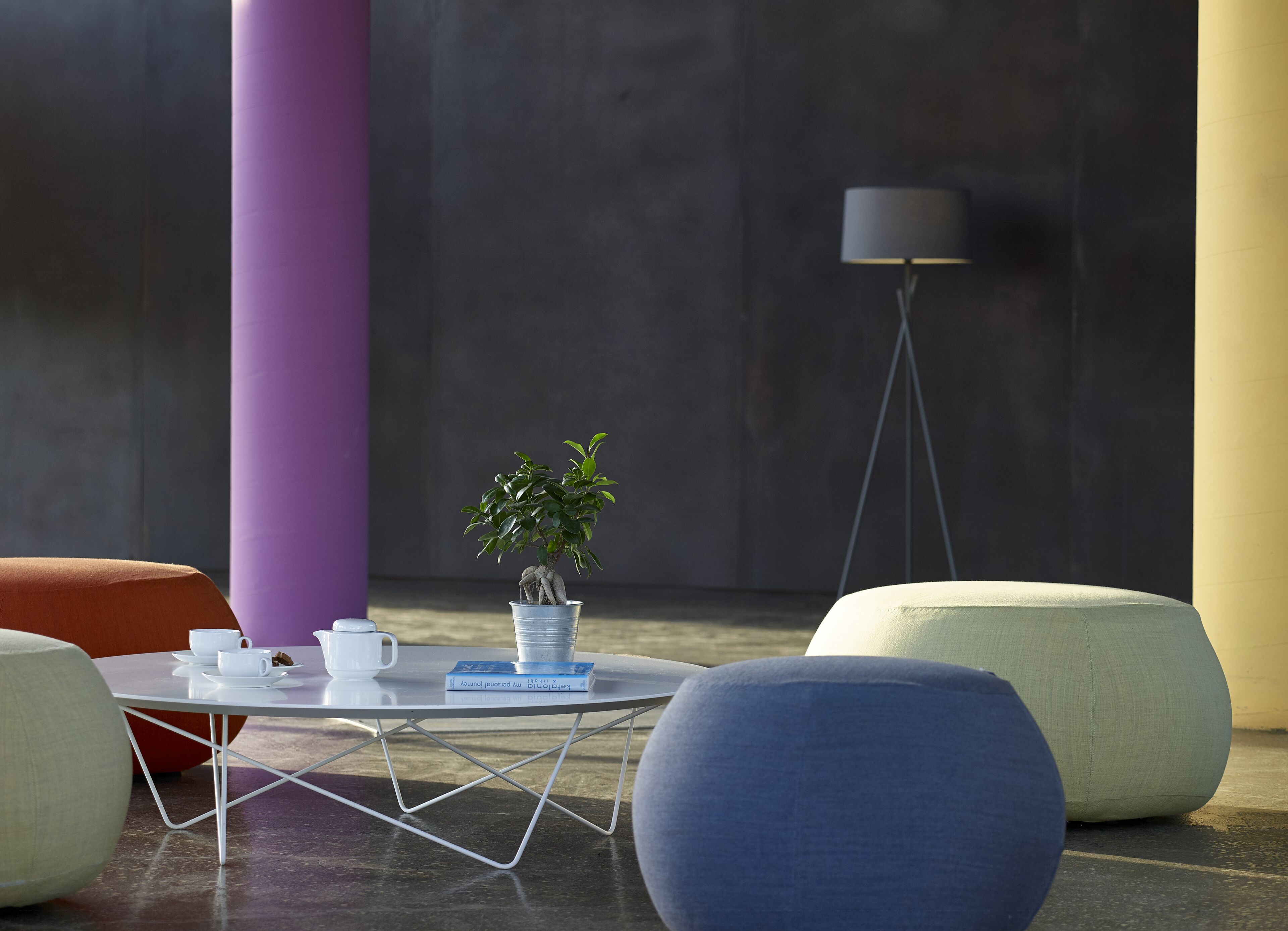 A modern lounge area with a round table, a potted plant, and a floor lamp.