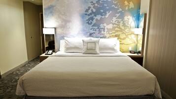Habitación de hotel con una cama grande, dos mesitas de noche, un teléfono y una pared con estampado de camuflaje.