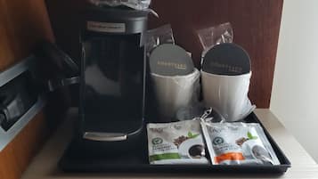 Una estación de café con una cafetera Hamilton Beach, dos tazas con la marca Courtyard y dos cápsulas de café Royal Cup.