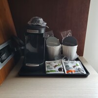 Una estación de café con una cafetera Hamilton Beach, dos tazas con la marca Courtyard y dos cápsulas de café Royal Cup.