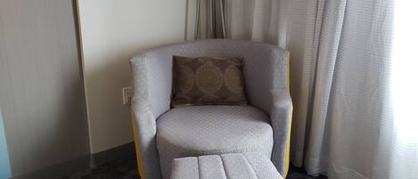 Un sillón moderno con un reposapiés a juego en una habitación de hotel.